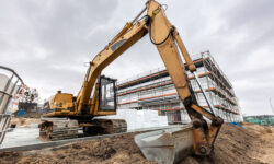 Excavator or digger working on office and warehouse building construction site.