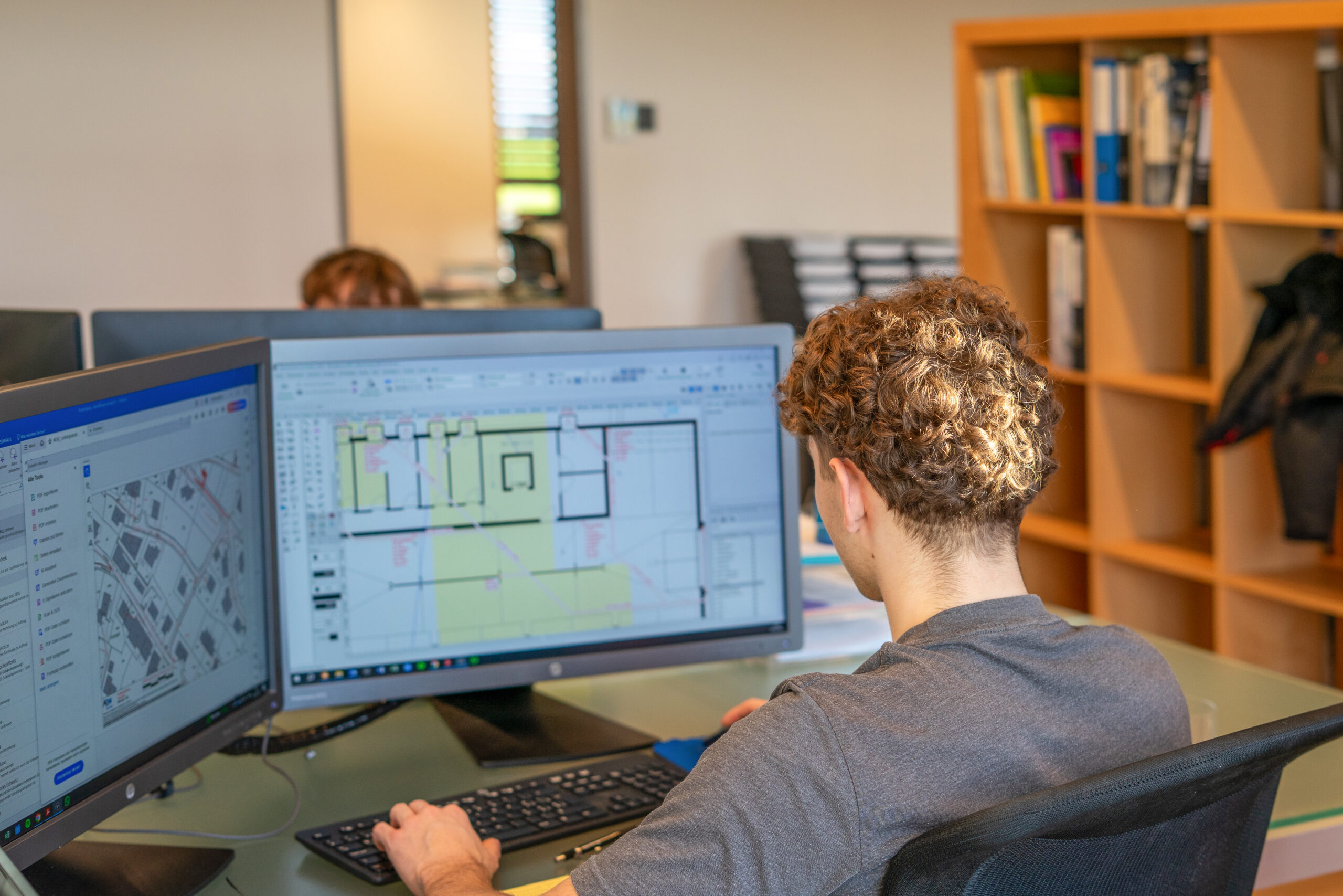 Mitarbeiter von Hausconcept arbeitet an einem Computer an einem Bauprojekt und hält Kunde über den aktuellen Stand am Laufenden.